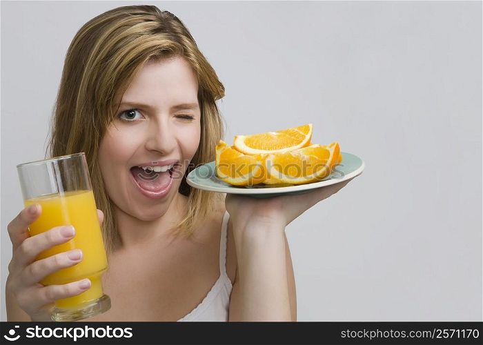 Portrait of a teenage girl holding a plate of oranges and a glass of orange juice