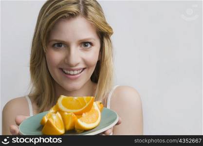 Portrait of a teenage girl holding a plate of oranges and smiling