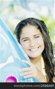 Portrait of a teenage girl holding a pool raft and smiling