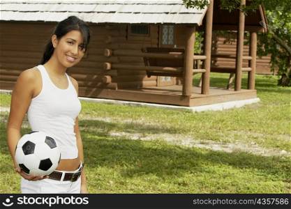 Portrait of a teenage girl holding a soccer ball and smiling