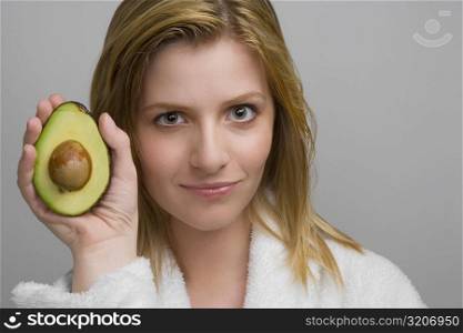 Portrait of a teenage girl holding an avocado and smiling