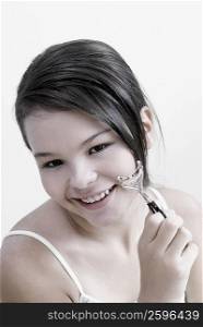 Portrait of a teenage girl holding an eyelash curler