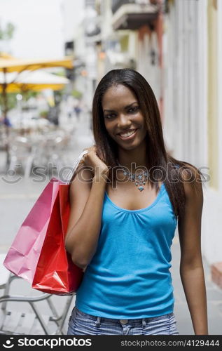 Portrait of a teenage girl holding shopping bags and smiling