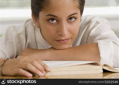 Portrait of a teenage girl leaning on a textbook