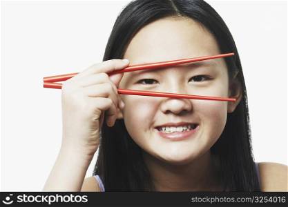 Portrait of a teenage girl looking through chopsticks
