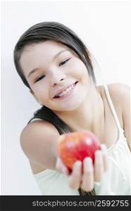 Portrait of a teenage girl offering an apple and smiling