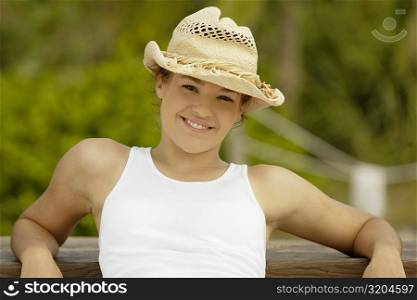 Portrait of a teenage girl posing against a wooden bench and smiling