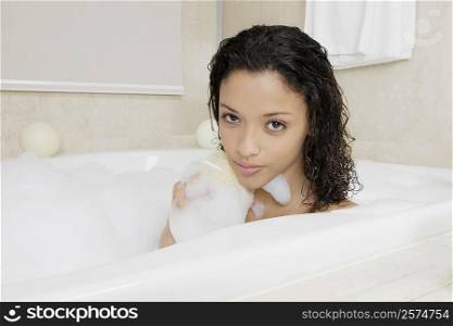 Portrait of a teenage girl scrubbing her back in the bathtub