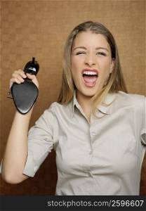 Portrait of a teenage girl shouting and holding a sandal