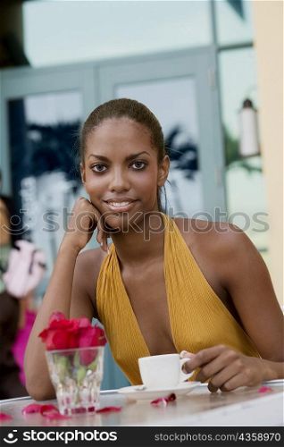 Portrait of a teenage girl sitting at a restaurant with a cup of coffee