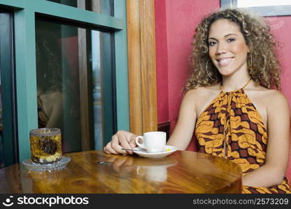 Portrait of a teenage girl sitting at a table with a cup of coffee