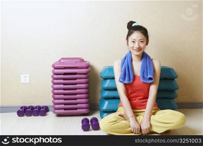 Portrait of a teenage girl sitting in front of stack of aerobic steps