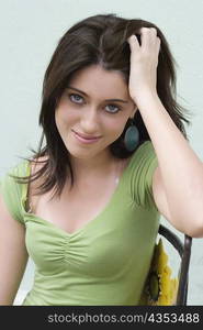 Portrait of a teenage girl sitting on a chair with her hand in her hair