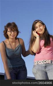 Portrait of a teenage girl smiling and her sister talking on a mobile phone