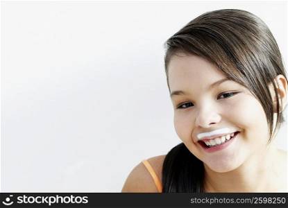 Portrait of a teenage girl smiling with a milk moustache