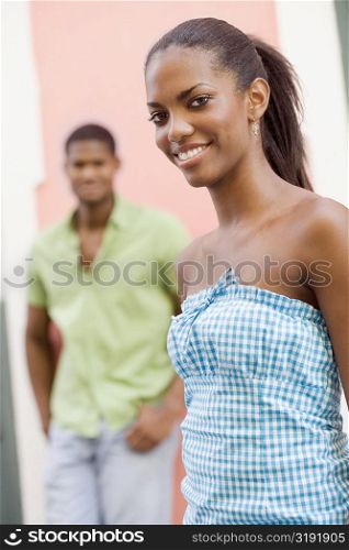 Portrait of a teenage girl smiling with a young man standing behind her
