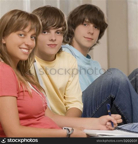 Portrait of a teenage girl smiling with her friends sitting beside her