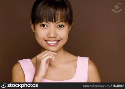 Portrait of a teenage girl smiling with her hand on her chin