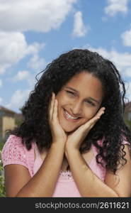 Portrait of a teenage girl smiling with her hands on her chin