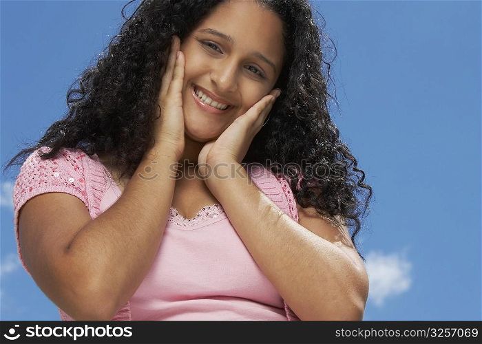 Portrait of a teenage girl smiling with her hands on her chin