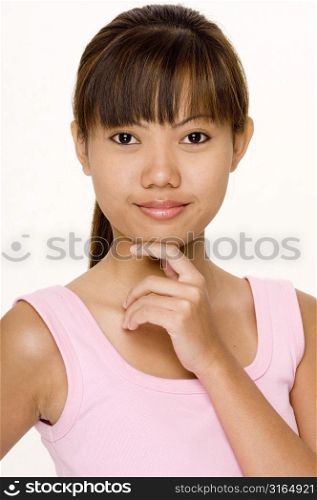 Portrait of a teenage girl smirking with her hand on her chin