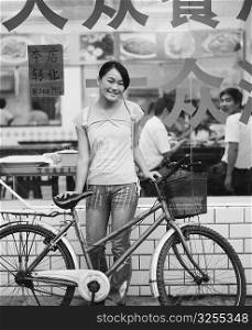 Portrait of a teenage girl standing with her bicycle in front of a restaurant