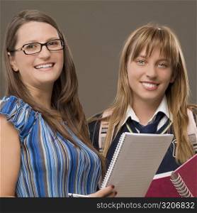 Portrait of a teenage girl standing with her female teacher and smiling