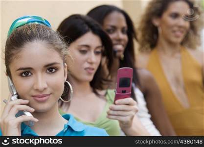 Portrait of a teenage girl talking on a mobile phone with three teenage girls behind her