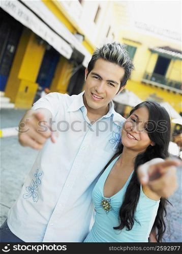Portrait of a teenage girl with a young man pointing forward and smiling