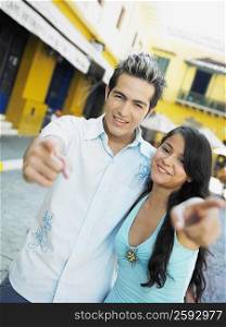 Portrait of a teenage girl with a young man pointing forward and smiling