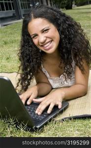 Portrait of a teenage girl working on a laptop and smiling