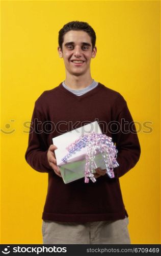 Portrait of a teenager boy holding a gift