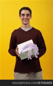 Portrait of a teenager boy holding a gift