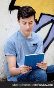 Portrait of a teenager guy with a tablet on a wall with graffiti background