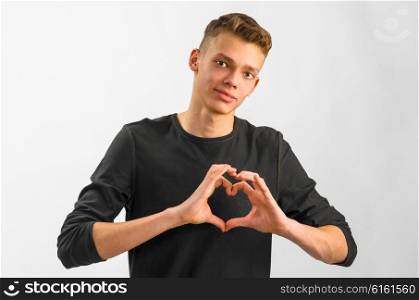 portrait of a teenager. male caucasian teenager is showing his love on gray background