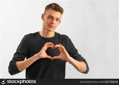 portrait of a teenager. male caucasian teenager is showing his love on gray background
