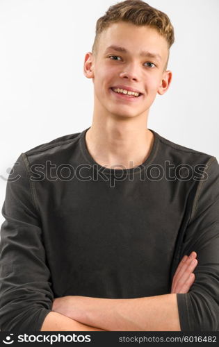 portrait of a teenager. portrait of a happy male caucasian teenager with folded hands on gray background
