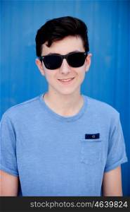 Portrait of a teenager rebellious man with sunglasses on a blue background