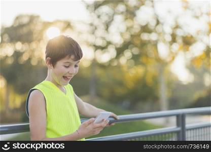 Portrait of a teenager smiling looking his smartphone on a basketball court