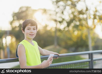 Portrait of a teenager smiling using his smartphone on a basketball court