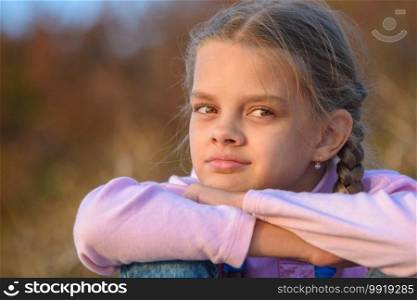 Portrait of a thoughtful beautiful ten-year-old girl at sunset