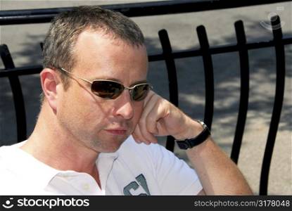 Portrait of a thoughtful man wearing sunglasses in outdoor cafe