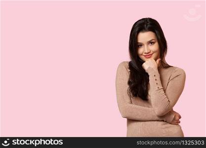 portrait of a thoughtful young beautiful girl in a light brown jacket on a pink isolated background.