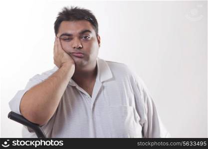 Portrait of a tired obese man with hand on face over white background