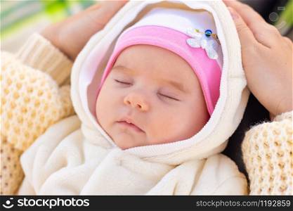 Portrait of a two-month-old baby sleeping on mom&rsquo;s feet in a park