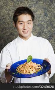 Portrait of a waiter holding a plate of noodles