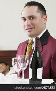 Portrait of a waiter holding a tray with a wine bottle and two wineglasses