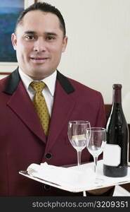 Portrait of a waiter holding a tray with a wine bottle and two wineglasses