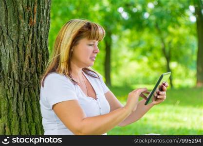 portrait of a woman 50 years old with a tablet in his hands in park