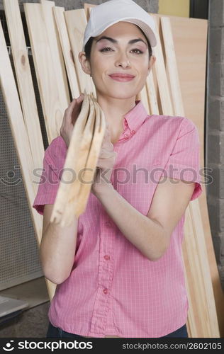 Portrait of a woman carrying wooden planks on her shoulder